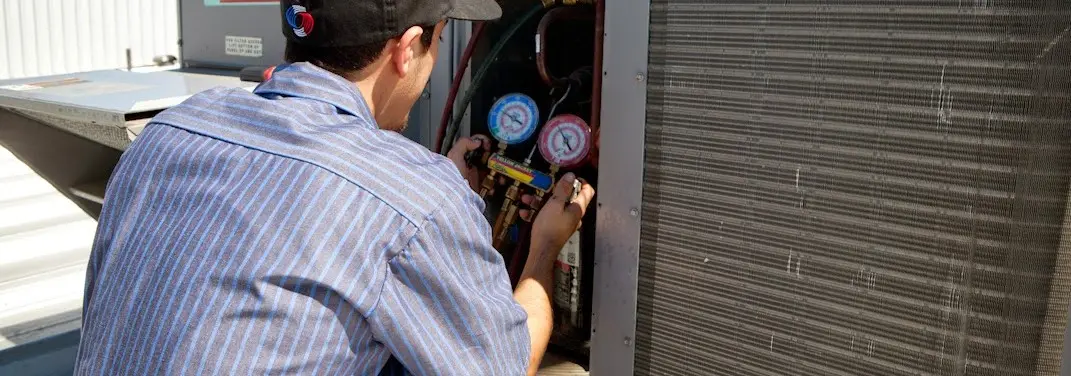 HVAC technician servicing a condenser unit in Cambria